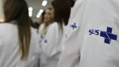 Profissionais de saúde usando jaleco com símbolo do SUS