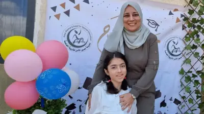 A mother stands over her seated daughter at a school celebration