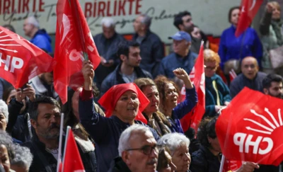 Ellerinde CHP bayrağı olan kadınlar ve erkekler toplu halde bir yere bakıyor,