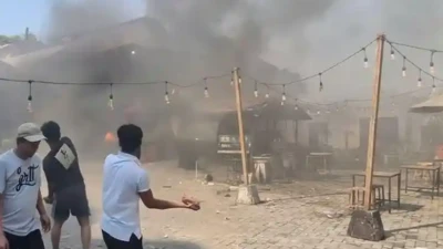 Warga terlihat melempari bangunan yang terbakar saat bentrokan di Jalan Tambak I, Menteng, Jakarta Pusat, Minggu (26/07). 