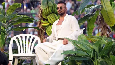 Ricky Martin sentado em uma cadeira monobloco, rodeado de vegetação, durante o show de Bad Bunny no intervalo do Super Bowl em 2026