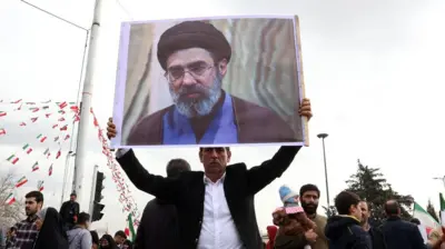 Seorang warga Iran mengusung foto Mojtaba Khamenei 