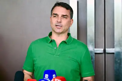 Flávio Bolsonaro usando uma camisa verde dando entrevista