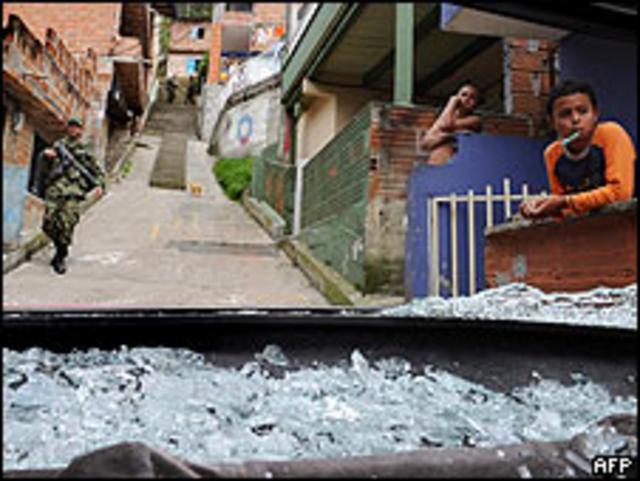 Soldado colombiano pasa delante de un auto destruido por las balas en Medellín (Archivo)