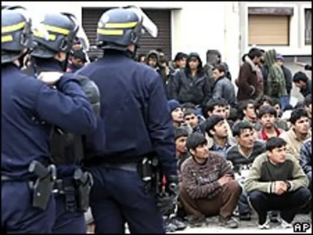 Полиция охраняет задержанных во время рейда против нелегальных мигрантов в Кале