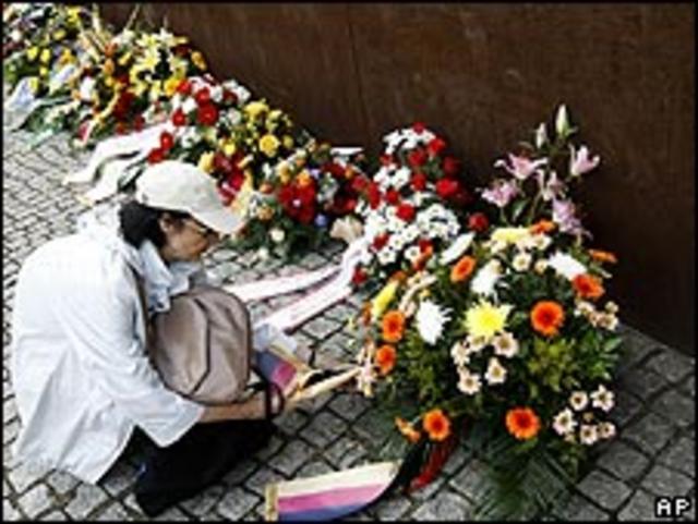 Mujer coloca flores para los caídos del Muro de Berlín