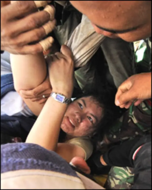 ایک عمارت کے ملبے کے نیچے سے ایک عورت کو نکالا جا رہا ہے