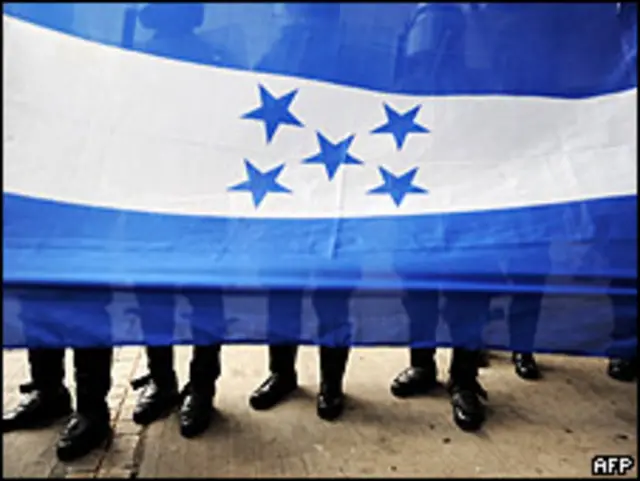 Agentes antimotines detrás de una bandera hondureña