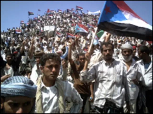 متظاهرون يرفعون العلم اليمني