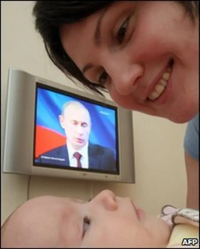 Женщина склонилась над около экрана телевизора, показывающего премьер-министра России Владимира Путина (архивное фото)