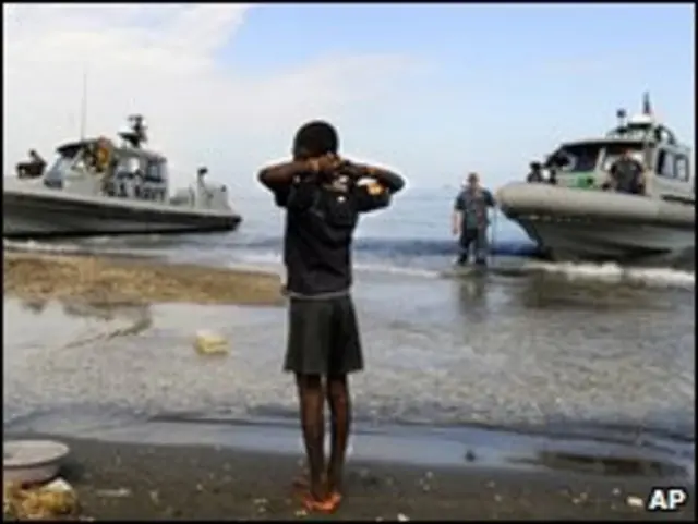 Menino haitiano observa navios americanos