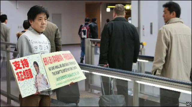 Feng Zhenghu mostra cartazes a passageiros em Tóquio