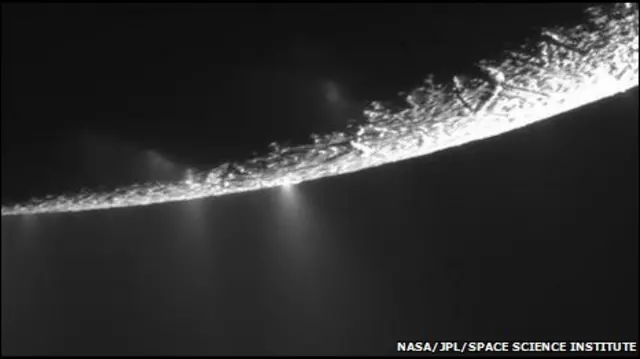 Partículas de gelo e vapor de água espirram por entre rachaduras na superfície da lua de Saturno