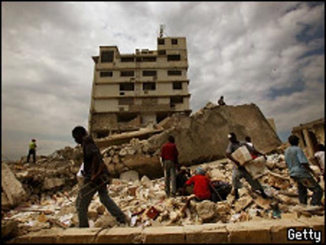 Haitianos sobre escombros de edifício desabado em Porto Príncipe