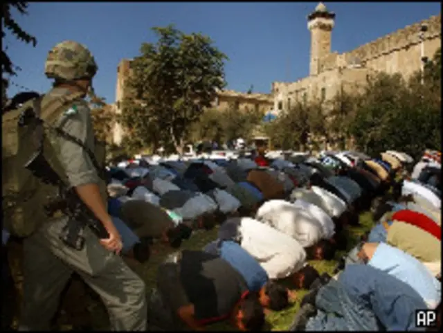 Soldado israelense vigia palestinos muçulmanos rezando (AP/Nasser Shiyoukhi)