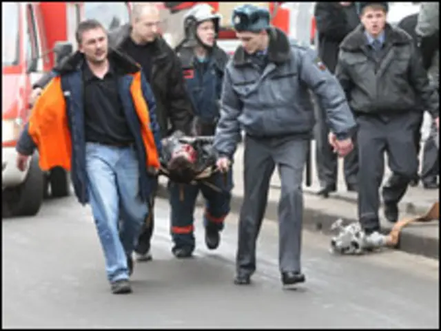 Спасатели несут пострадавшего при взрыве на носилках 