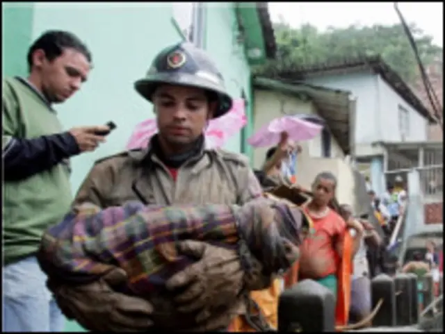 Bombeiro retira corpo de criança do Morro do Borel (foto: AFP)
