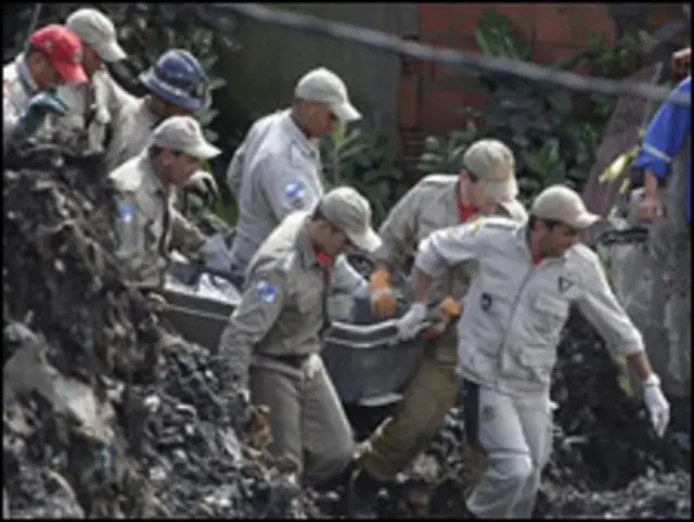 Bombeiros levam corpos no Morro do Bumba.