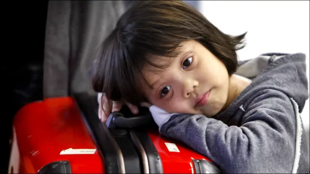 Niña descansa sobre su maleta