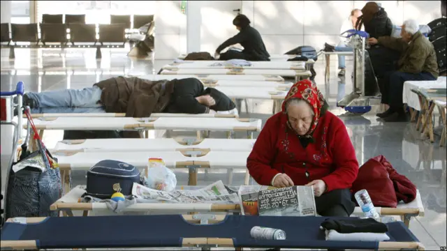 Mujer mayor leyendo el periódico en el aeropuerto
