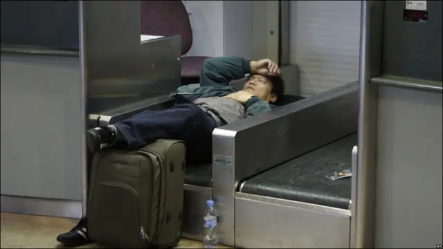 Pasajero durmiendo en la cinta transportadora de un mostrador