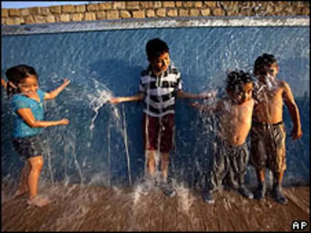 Niños juegan bajo una fuente de agua en Monterrey, México