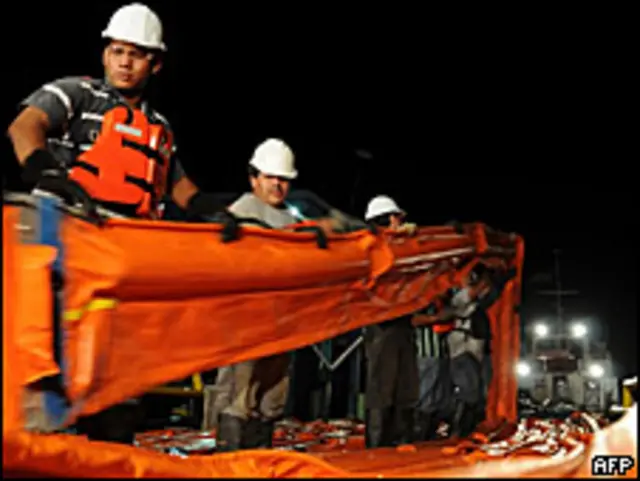 Trabajadores mueven mallas para contener el derrame de petróleo