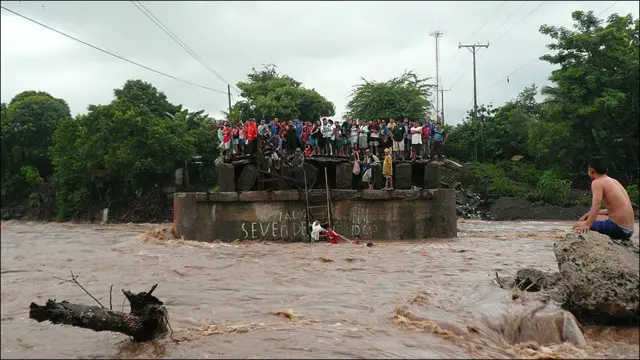 Un grupo de personas se protege de la crecida de un río.