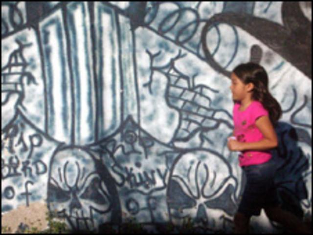 Una niña pasea frente a un graffiti de la Mara Salvatrucha, que controla la comunidad 22 de abril en el municipio de Soyapango. 