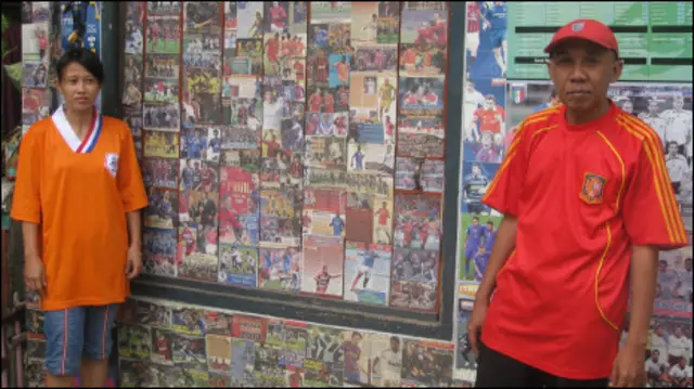 Susilo dan istrinya mengenakan kaus Spanyol dan Belanda di depan kediaman mereka yang dilapisi poster-poster sepak bola.