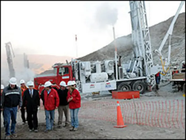 Dos hombren colocan una bandera de Chile sobre la mina.