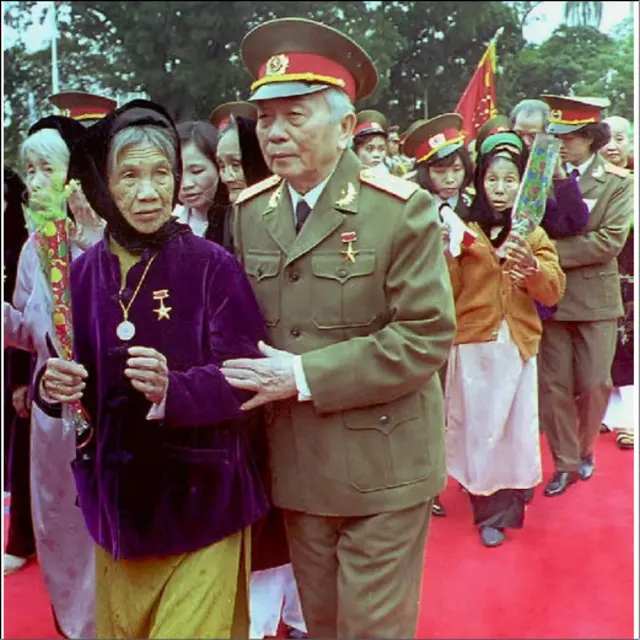 Vị tướng đi cùng một "Bà mẹ Việt Nam anh hùng" tại buổi lễ ngày 19/12/1994 vinh danh những bà mẹ có người thân hy sinh cho chính phủ cộng sản trong cuộc chiến chống Pháp và Mỹ.  