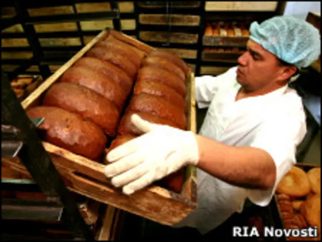 Рабочий держит поднос с хлебом