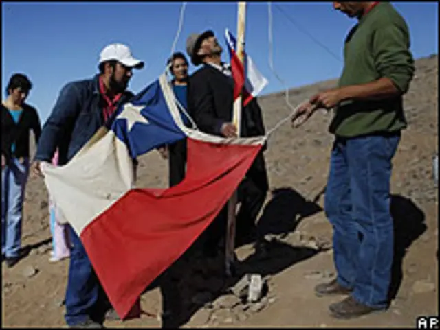 Familiares de mineros chilenos izan una bandera junto a la mina.