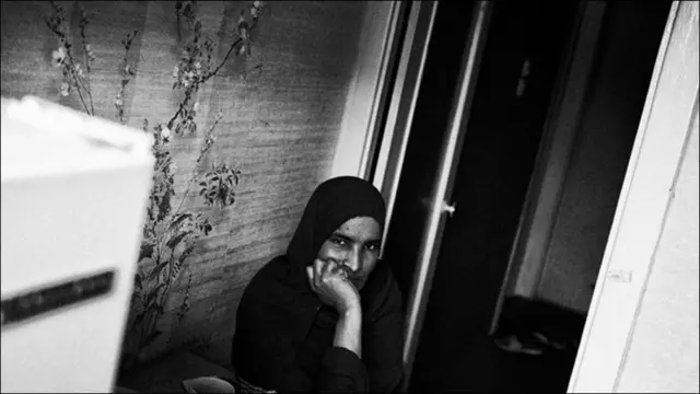 Женщина в черном сидит на стуле в комнате