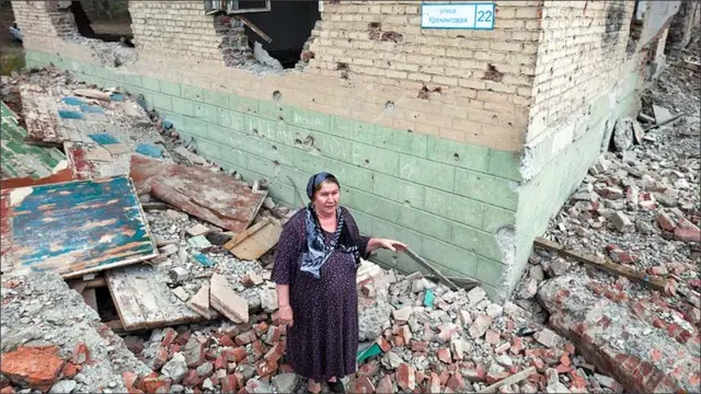 یہ عورت ابھی تک تباہ شدہ مکان میں رہائش پذیر تھی۔ اب انہیں نئی جگہ منتقل کیا گیا ہے لیکن وہ کہتی ہیں کہ ان کے پاس نئی جگہ کے مالکانہ حقوق نہیں ہیں۔ 