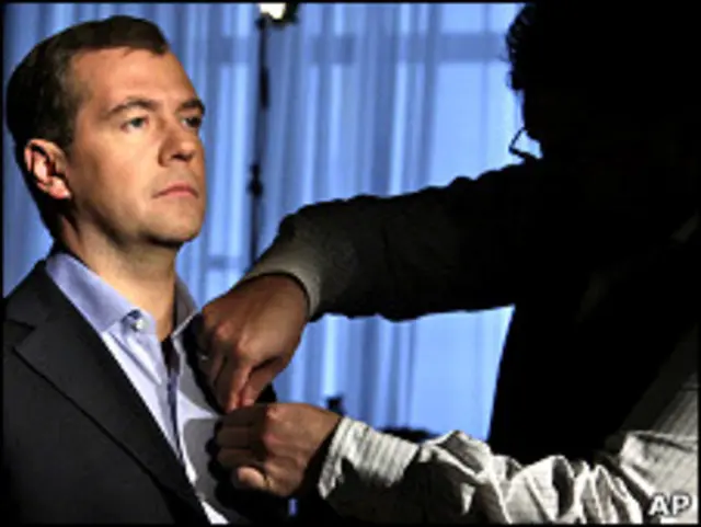 Помощник прикрепляет к костюму президента России Дмитрия Медведева микрофон