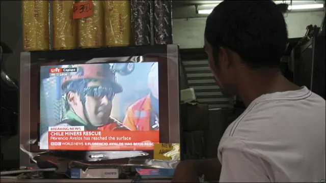 Un filipino ve las imágenes del rescate en televisión.