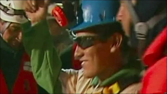 Carlos Mamani con lentes y un casco saluda al salir de cápsula