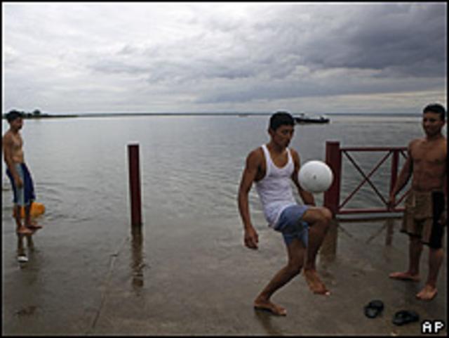 Chicos juegan con una pelota de fútbol en la orilla del río San Juan.