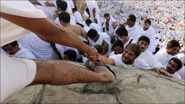 Un musulmán ayuda a otro para subir el Monte Arafat
