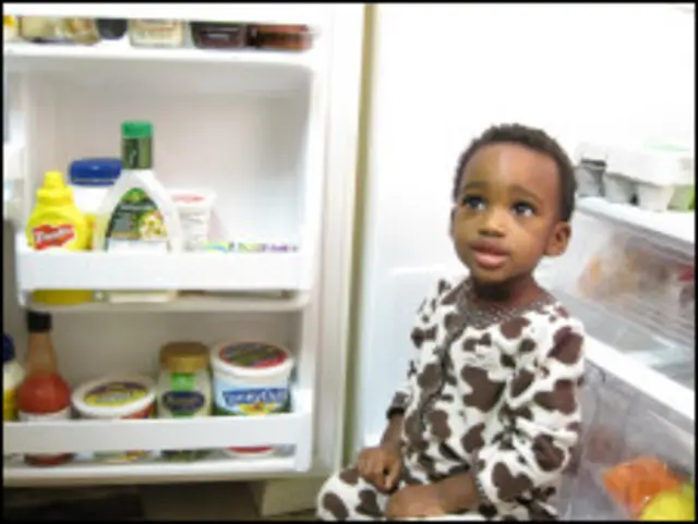 Девочка сидит у открытого холодильника