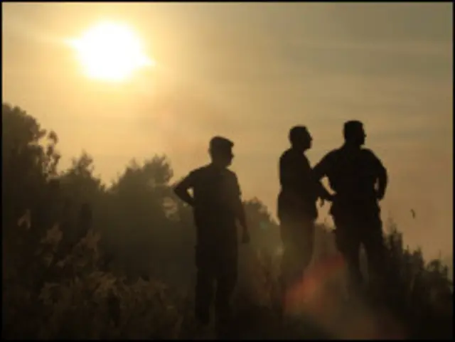 عناصر من قوى الأمن يتأملون الحرائق في منطقة الجمهور