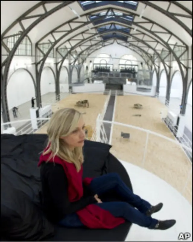 Mulher sobre cama instalada na exposição