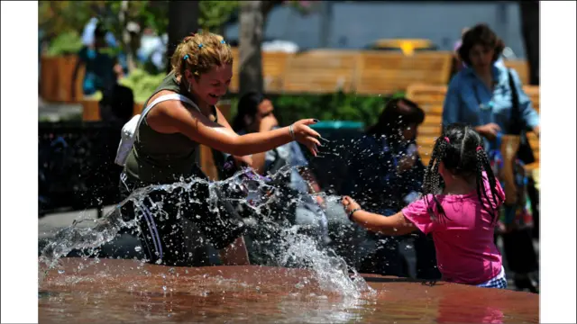 د سانتیاګو په پلازا د آرماس سیمه کې یوه ماشومه له خپلې مور سره د اوبو له نلکې سره لوبې کوي.
