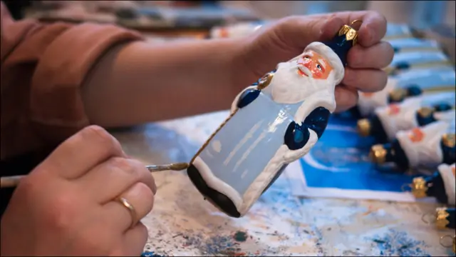 Художница расписывает фигурку Деда Мороза 