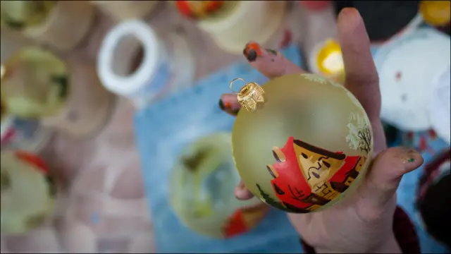 Художница держит елочный шар 