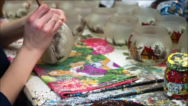 Художница расписывает елочную игрушку