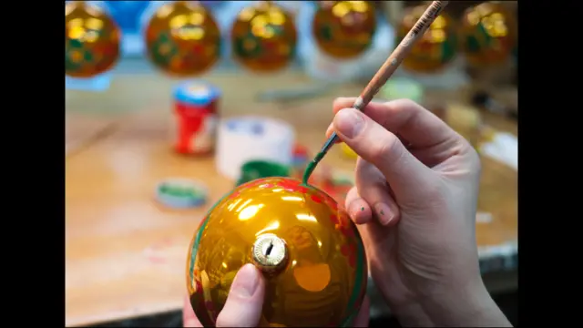 Художница расписывает шар под хохлому
