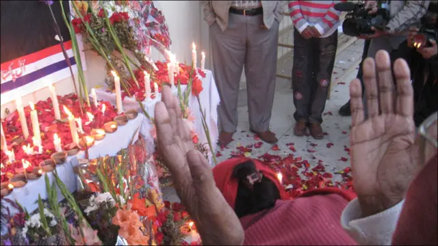 سلمان تاثیر کی تصویر کے سامنے ان کا ایک چاہنے والا مسیح ہاتھ اٹھا کر دعا مانگ رہا ہے۔